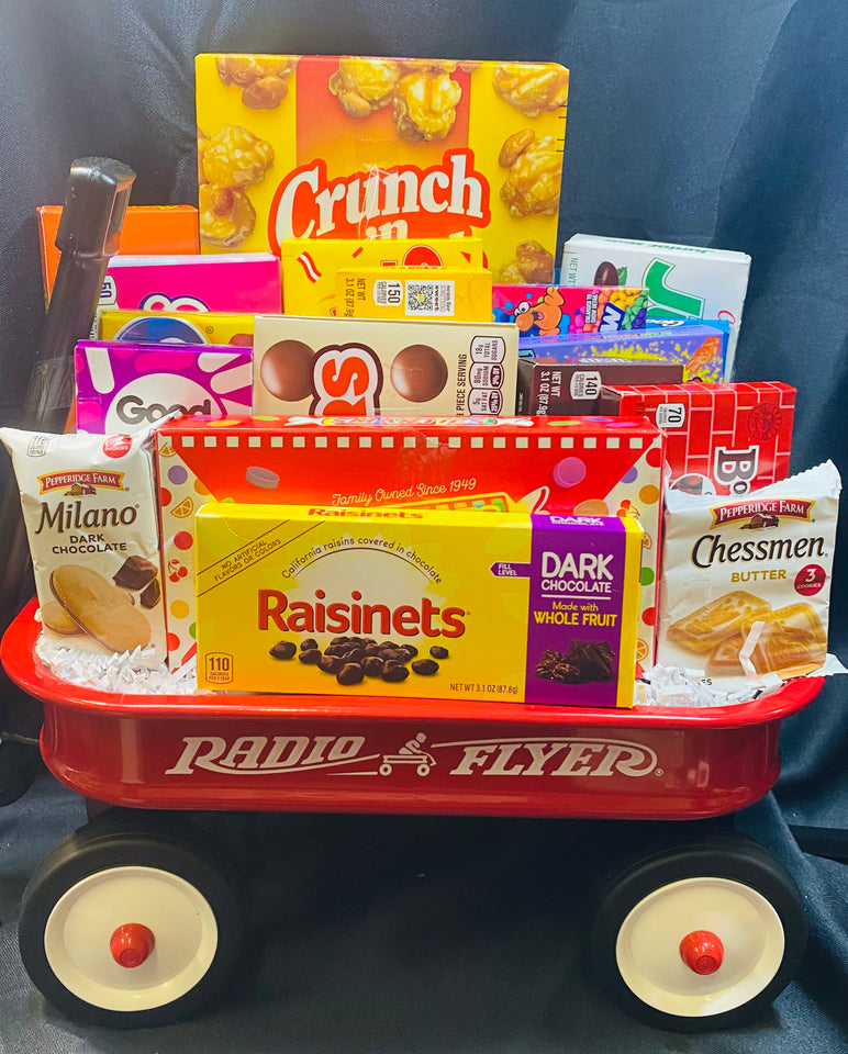 Miniature red Radio Flyer wagon filled with various snacks on a dark background