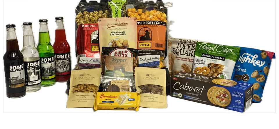 A variety of snack and beverage products arranged together on a white background, including four bottles of soda, bags of popcorn, pretzels, chips, cookies, and crackers.