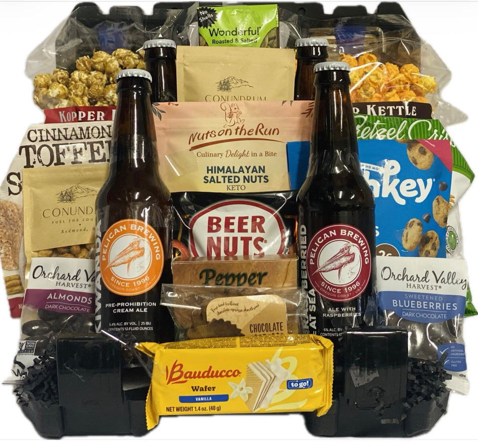 A curated snack and beer gift basket arranged in a black plastic tray, featuring two bottles of Oregon Brown Ale, several bags of nuts and chocolates, and packaged treats from brands like Conundrum and Baudoucci.
