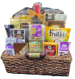 A wicker basket containing an assortment of gourmet snacks including popcorn, crackers, cheeses, biscuits, cookies, pretzels, summer sausage, fruit candies, nuts, and a bottle of wine.